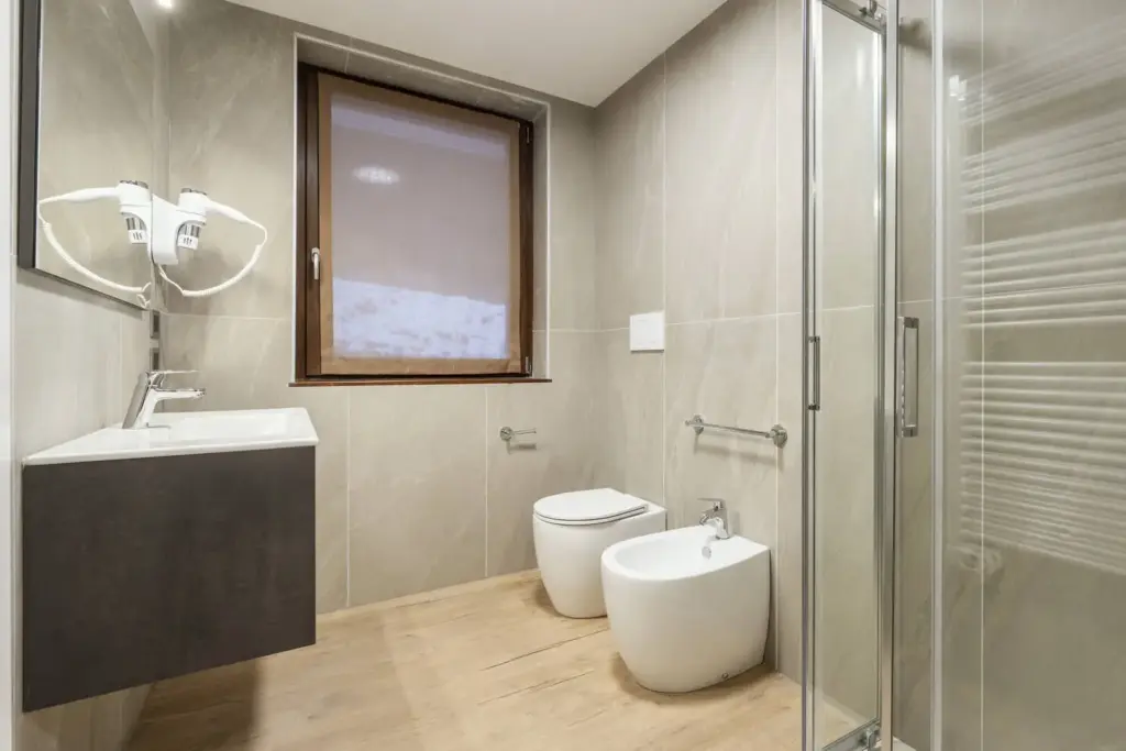 Bagno luminoso con doccia moderna e pavimento in legno.