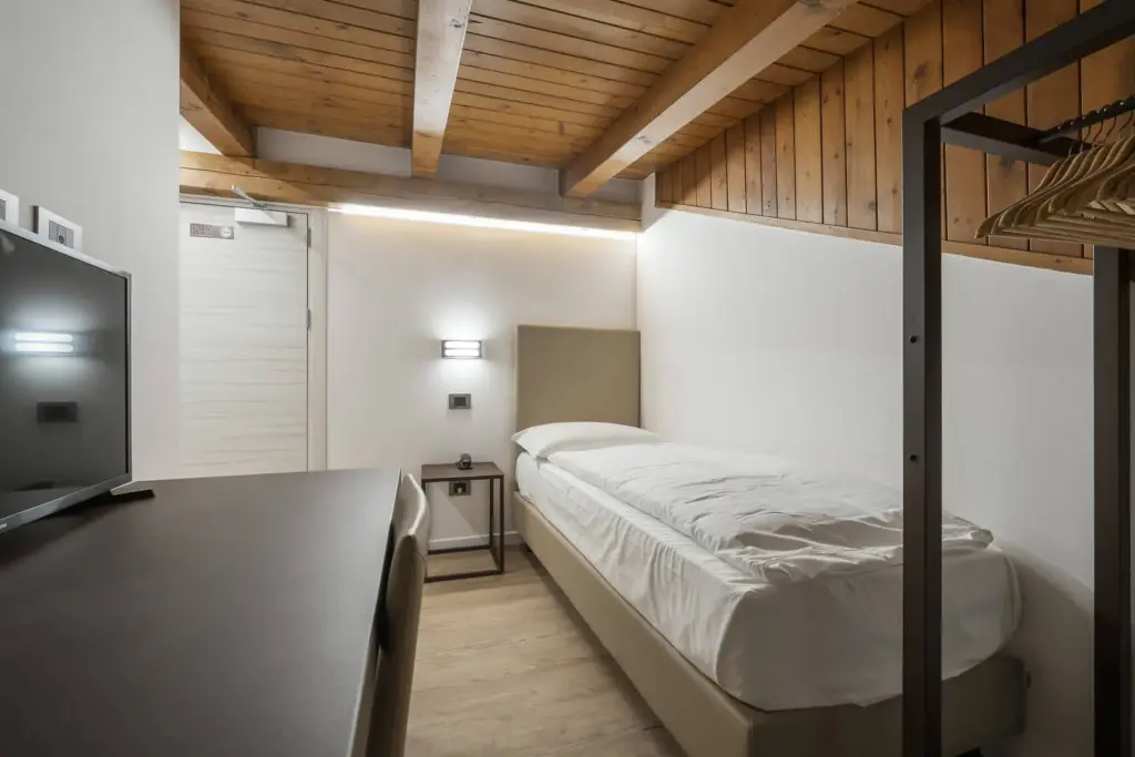 Camera singola accogliente con soffitto in legno.